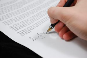 Hand holding a pen signing a document.